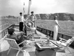 Entre deux verres, "Le Parisien" (Julien Carette) raconte sa vie à Florence (Arletty) et à son mari Michel Brabant (Maurice Teynac), à la barre du yacht dans "La Fleur de l'âge" de M. Carné et J. Prévert, Belle-Ile, 1947